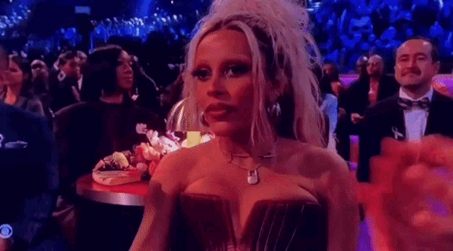 a woman in a strapless dress is sitting in a crowd of people at a awards show .