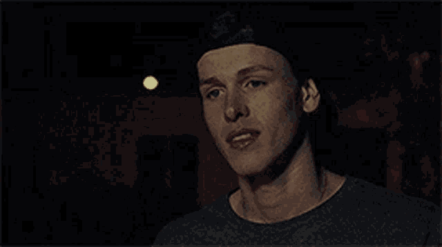 a close up of a man 's face in a dark room with a light behind him