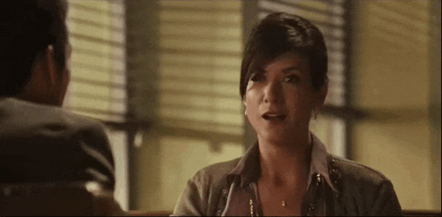 a woman is talking to a man while sitting at a table .