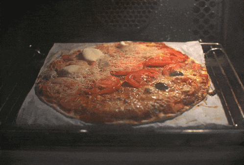 a pizza is sitting on a piece of wax paper inside of an oven