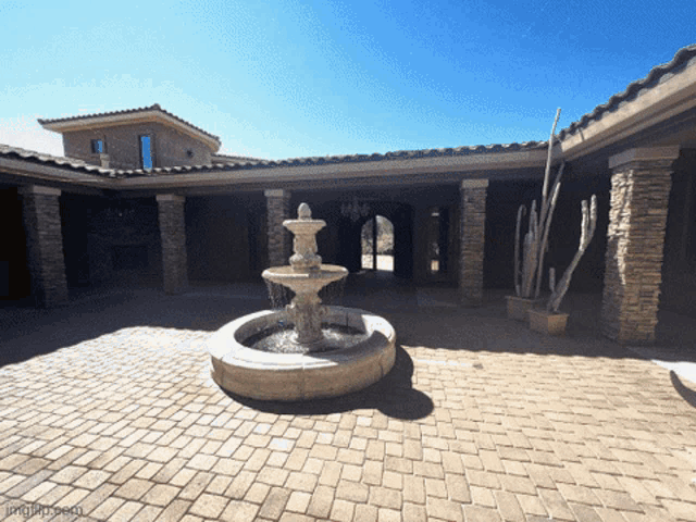 a brick courtyard with a fountain and a cactus