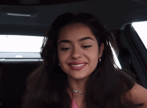 a woman with a nose ring is smiling in the back seat of a car