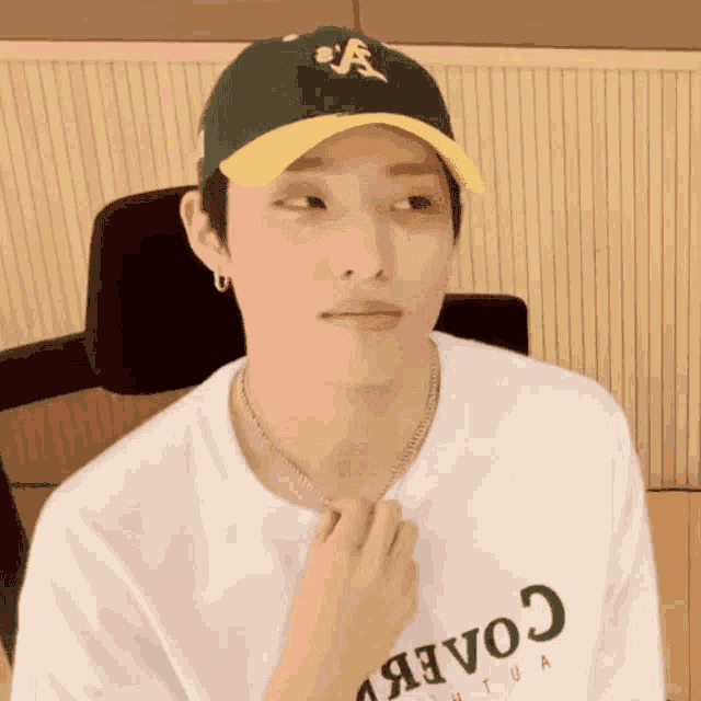 a man wearing a baseball cap and a white shirt is sitting in a chair .