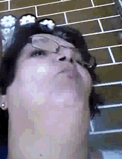 a woman wearing glasses and a hat looks up at the sky