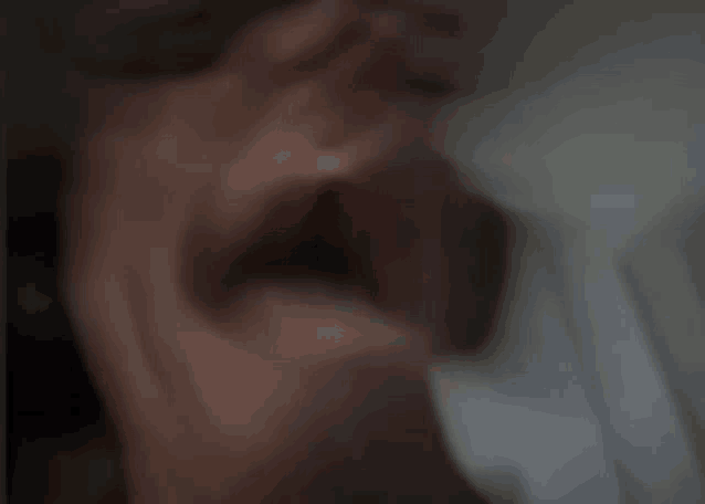 a blurry picture of a person 's face with their hand covering their mouth