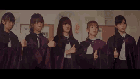 a group of girls are standing next to each other giving a thumbs up .