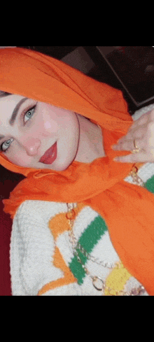 a woman wearing a scarf and a sweater has a ring on her finger