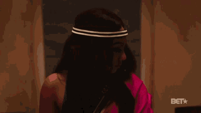 a woman is wearing a headband and a pink saree with a bet star in the corner