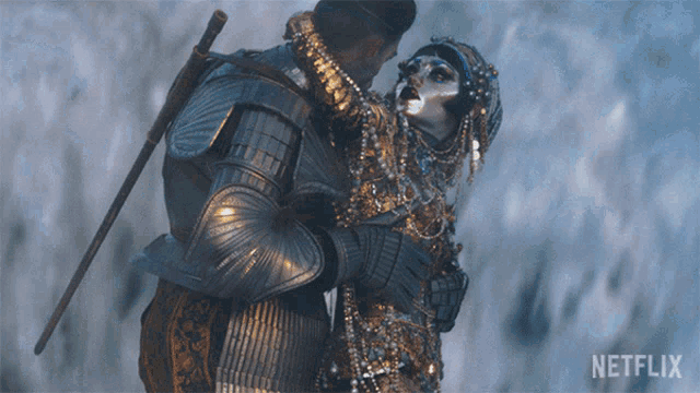 a man in armor is hugging a woman with a netflix logo behind them