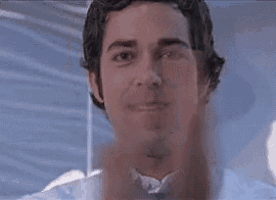 a close up of a man in a white shirt and tie making a hand gesture .