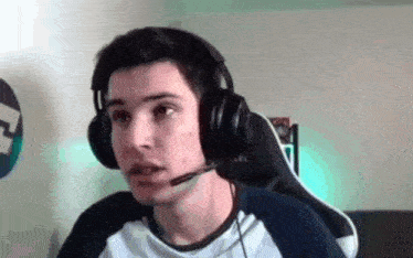 a young man is wearing headphones and a microphone while sitting in a chair .