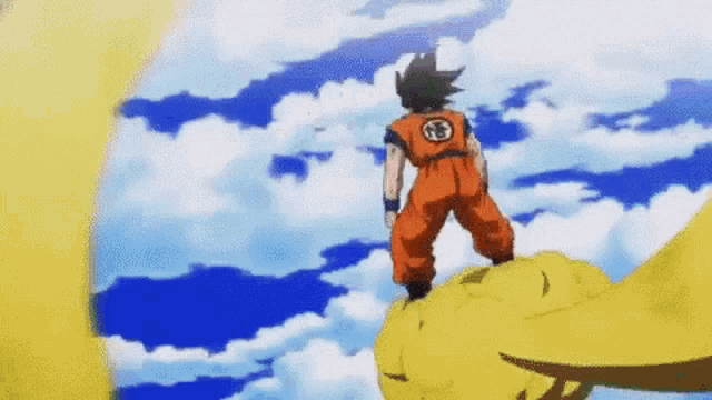 goku from dragon ball z is standing on top of a yellow ball .