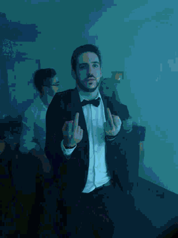 a man in a tuxedo and tie is giving the middle finger