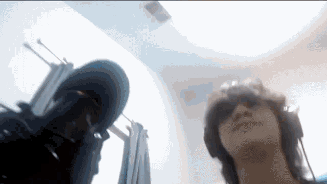 a man wearing headphones and sunglasses is standing next to another man in a room .