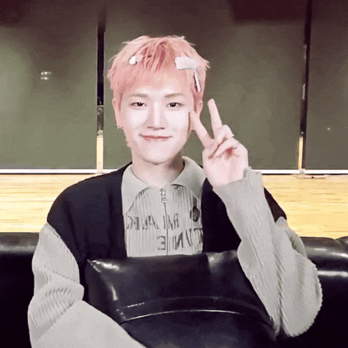 a young man with pink hair is wearing a shirt that says ' a ' on it