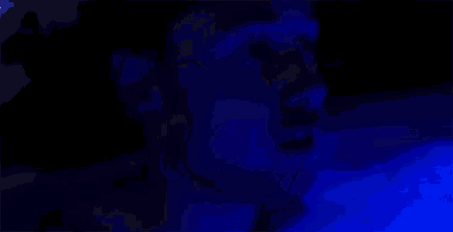 a close up of a person 's face in a dark room with blue lights .