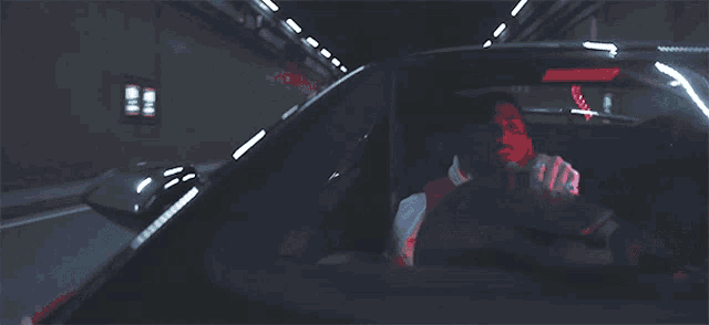 a man is driving a car in a dark tunnel