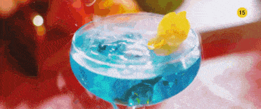 a blue drink in a martini glass with a yellow flower on top and the number 15 on the bottom