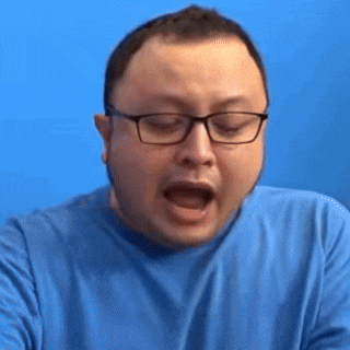 the man is wearing glasses and a blue shirt and is making a funny face .