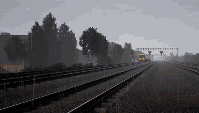 a yellow train is going down the tracks in the rain