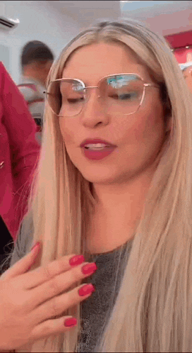 a woman wearing glasses and red nails is looking down .