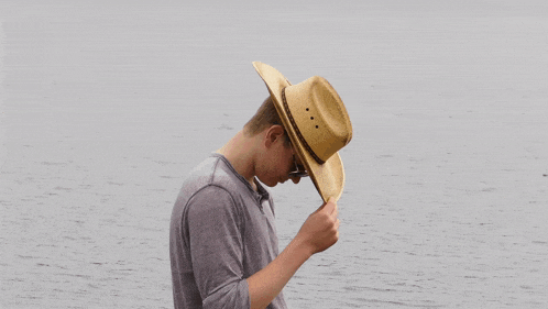 a man wearing a cowboy hat adjusts his sunglasses