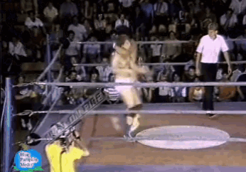 a man in a yellow shirt stands in a wrestling ring with a sign that says " big pumpkin media " on it