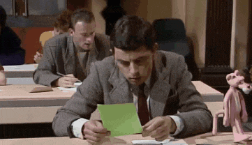 a man in a suit and tie is sitting at a desk looking at a piece of paper .