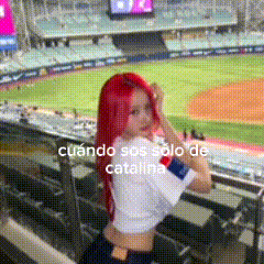 a woman with red hair is standing in front of a baseball stadium