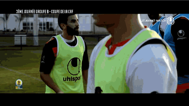 a soccer player wearing a yellow uhlsport vest