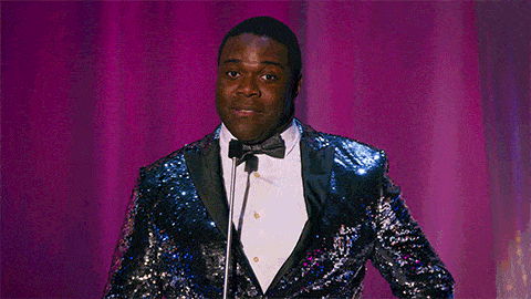 a man in a sequined suit and bow tie is standing in front of a microphone