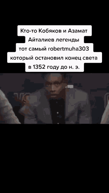 a man in a suit is sitting in front of a sign that says " kto-to kobykov i azamat "