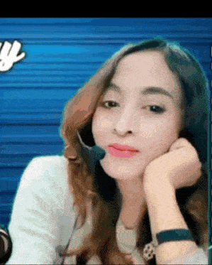 a woman wearing a headset looks at the camera with her hand on her face