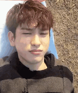 a young man is laying on a blanket with his eyes closed and making a funny face .
