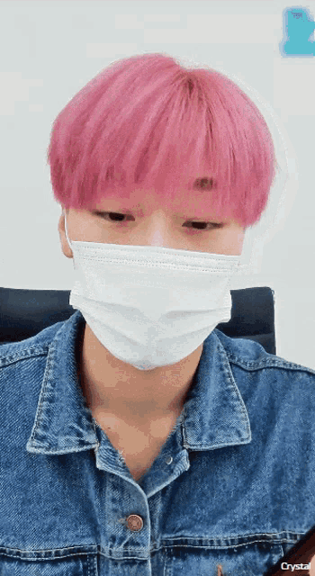 a person with pink hair is wearing a white face mask