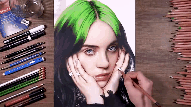 a drawing of billie eilish with green hair is on a table surrounded by pencils