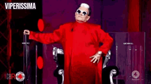 a man in a red suit and sunglasses is holding a microphone and says io sparerei a lei .