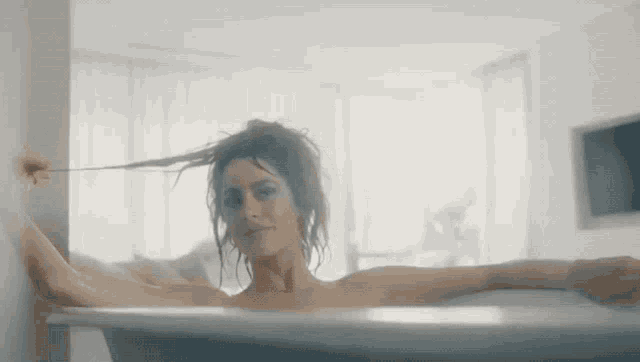 a woman is taking a bath in a bathtub while holding her hair