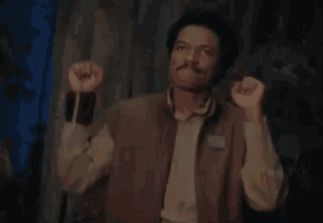 a man with a mustache is raising his fist in the air