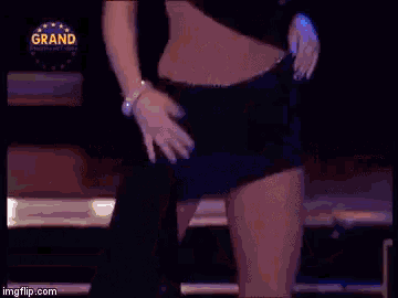a woman in a black dress is dancing in front of a sign that says grand on it