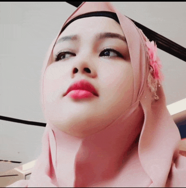 a close up of a woman wearing a pink hijab with a flower in her hair