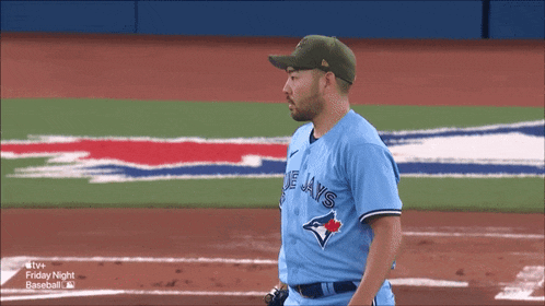 a man wearing a blue jays jersey stands on the field