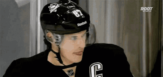 a hockey player wearing a black helmet and a black jersey with the number 87 on it .
