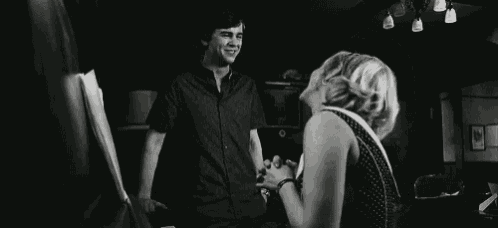 a black and white photo of a man and a woman laughing in a room .