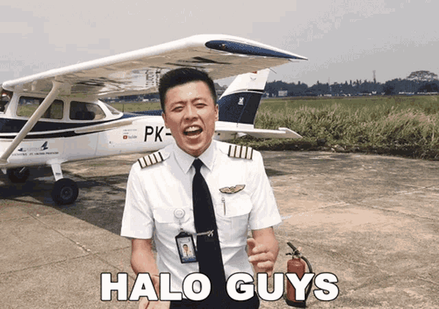 a man in a pilot 's uniform is holding a fire extinguisher in front of a plane that says pk on it