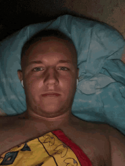 a shirtless man laying on a bed with a blanket that says ' a ' on it