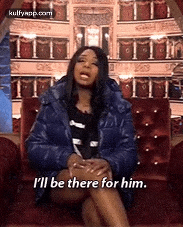 a woman in a blue jacket is sitting on a red couch and says `` i 'll be there for him '' .