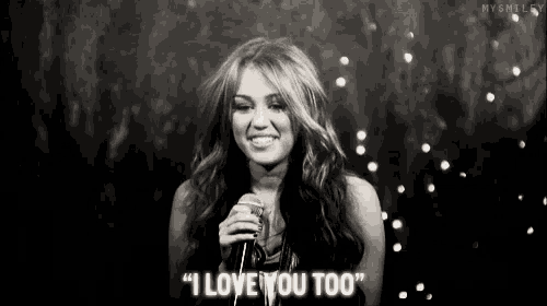 a woman singing into a microphone with the words " i love you too " on the bottom