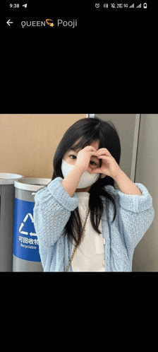 a little girl wearing a face mask making a heart shape with her hands