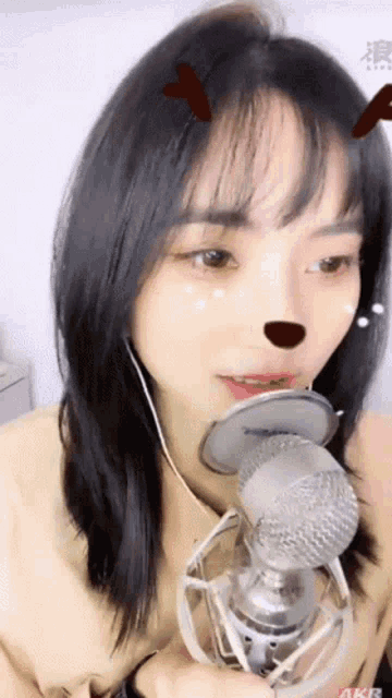 a girl is singing into a microphone while wearing earbuds